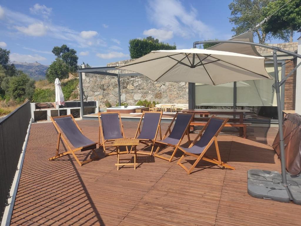 Espreguiçadeiras e chapéu de sol no deck, com a serra ao fundo