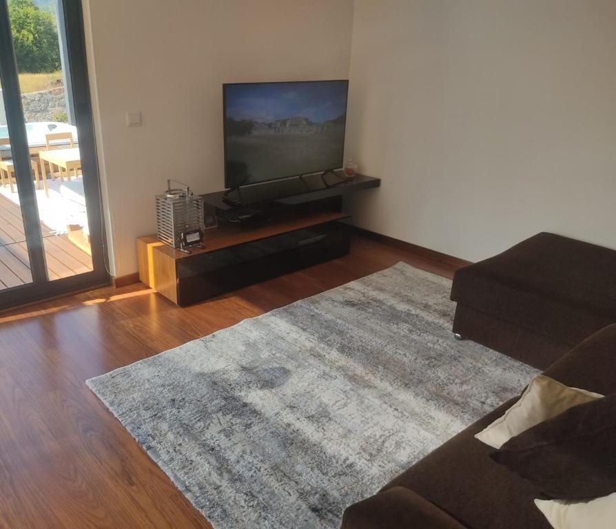Sala com sofá e televisão, aberta para o deck por portas envidraçadas